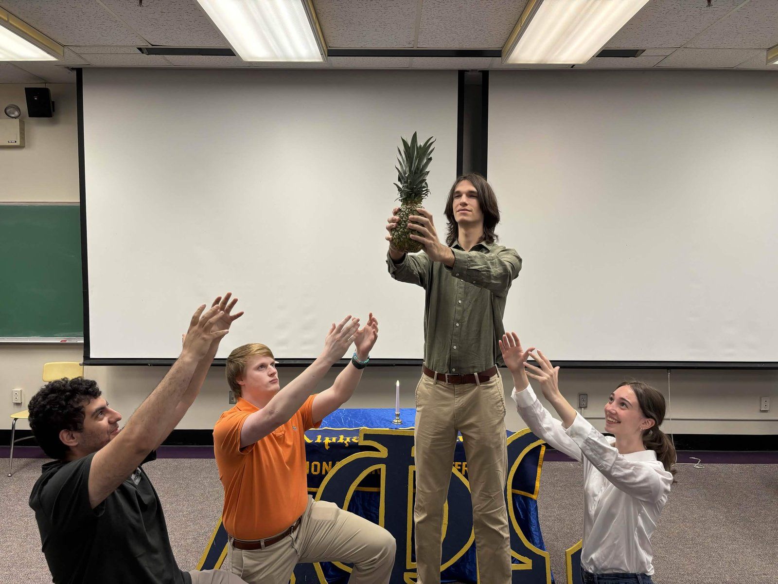 Alpha Phi Omega members raising a pineapple during a Big/Little ceremony
