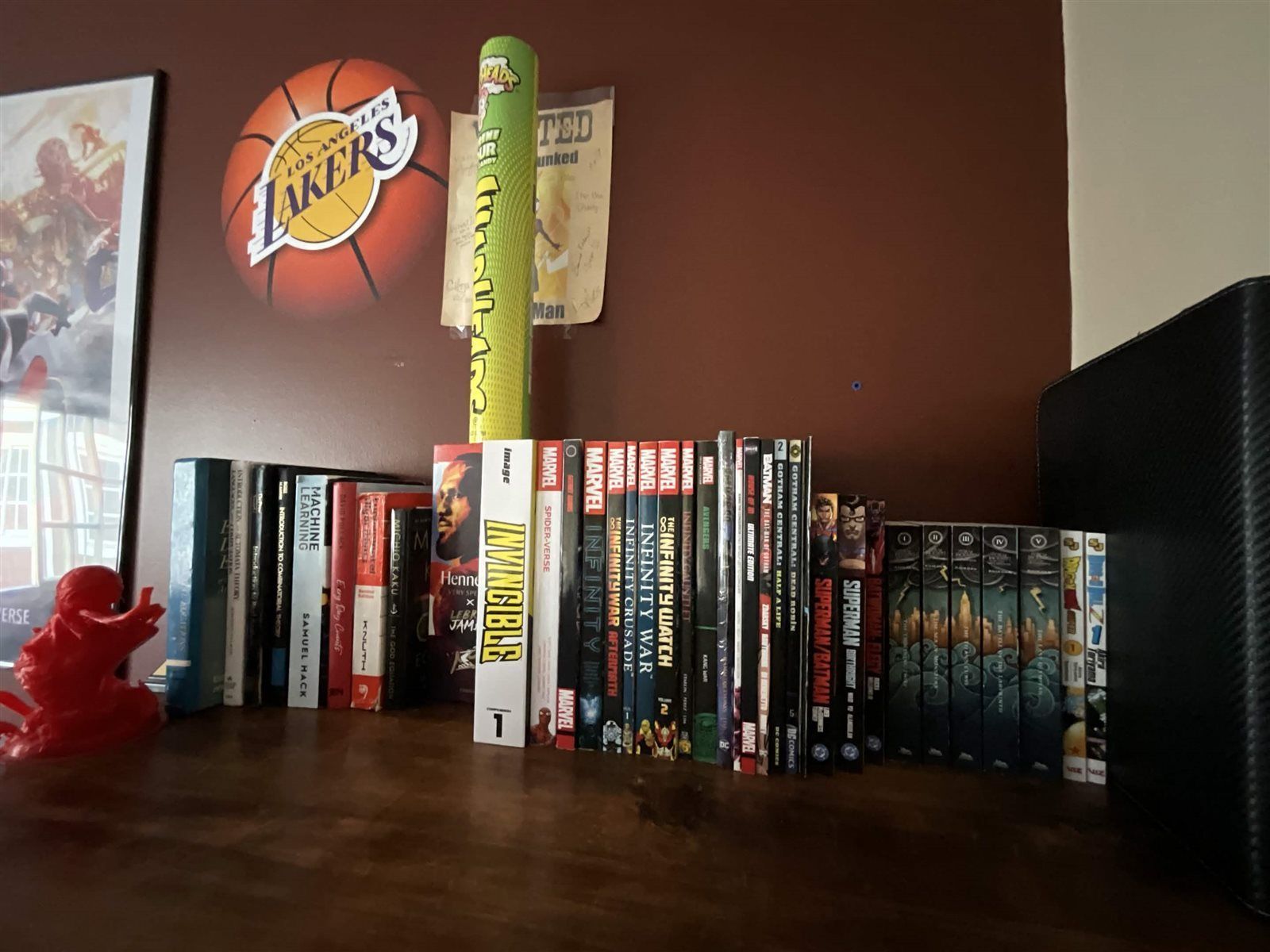 Armaan's bookshelf with comics, graphic novels, and a Los Angeles Lakers logo above it